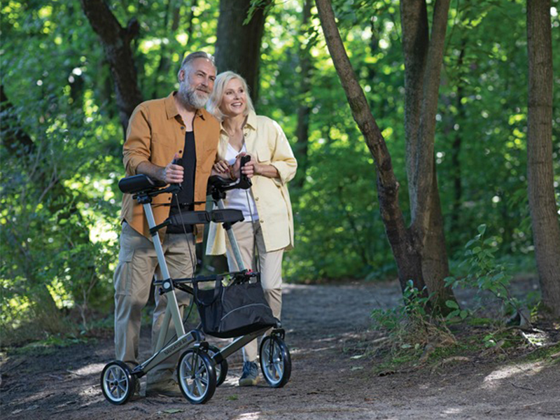 Mann schiebt Navigator Air Rollator über eine Wiese im Wald