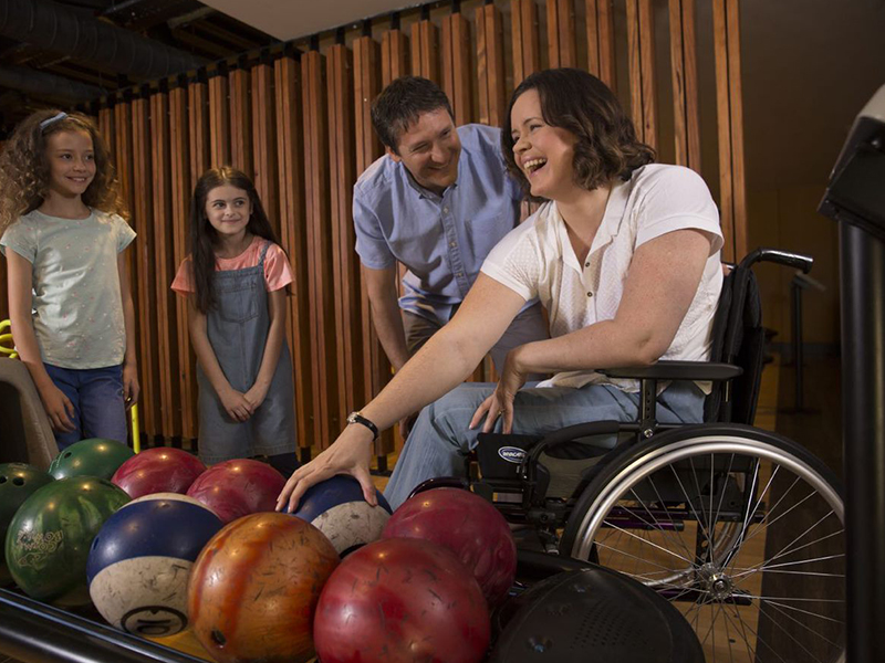 Frau sitzt in Leichtgewichtrollstuhl von Invacare an einer Bowlingbahn