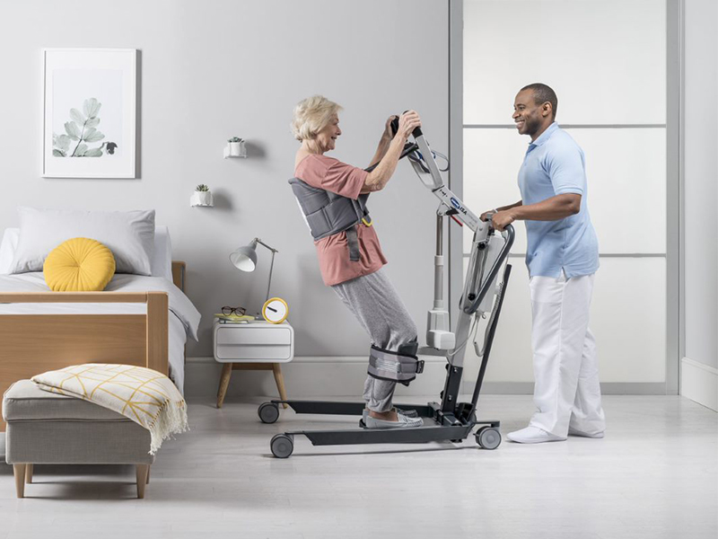 Mann hebt ältere Frau mit Patientenlifter ISA an